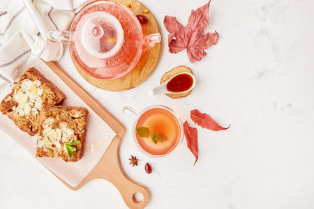 Homemade cinnamon apple pie and glass teapot with cup of cranberry dogwood tea - aesthetic autumn table setting among leaves. Cope space.の写真素材