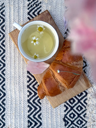 Cup of herbal tea with croissant . Quiet break in nature, wellness mood, and simplicity in one shot.の写真素材