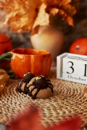 Autumn Halloween cookies in shape of spider and cup of tea in shape of pumpkin near 31 of October on calendarの写真素材
