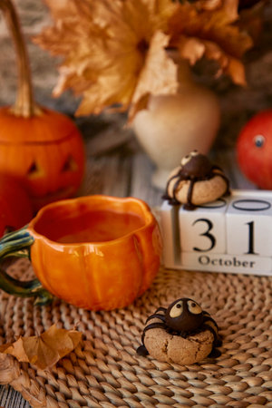Traditional fall Halloween still life - cookies in shape of spider and cup of tea among pumpkins and Jack o lantern. 31 of October on calendarの写真素材