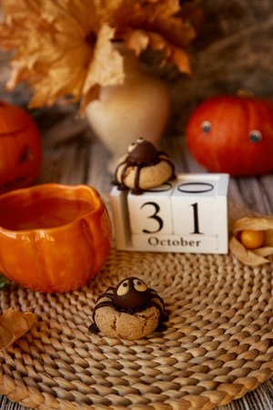 Autumn Halloween still life - funny cookies in shape of spider and cup of tea in shape of pumpkin. 31 of October on calendarの写真素材
