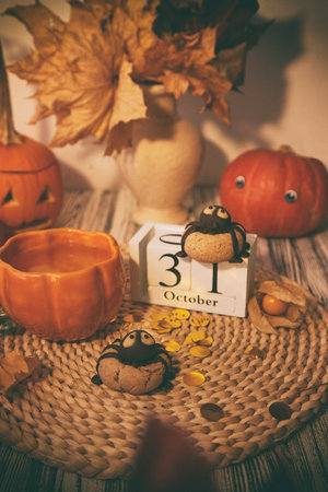 Traditional autumn Halloween cookies in shape of spider and cup of tea among pumpkins. 31 of October on calendarの写真素材