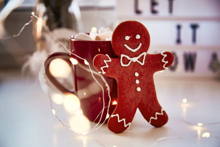Homemade gingerbread cookie with festive bokeh decor on Let it snow background. Christmas decorations with hot drink and marshmallows. Aesthetic Christmas atmosphere, home coziness, warmth conceptの写真素材