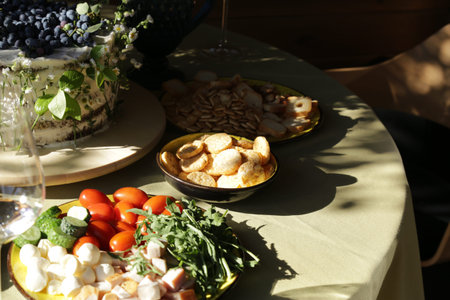Fresh appetizer plate with cherry tomatoes, cucumber, mozzarella and sliced meat on rustic party...