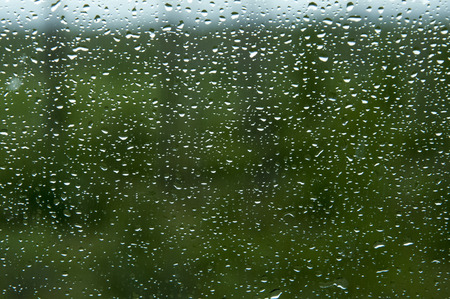 Many small drops of the rain on the glass on green backgroundの写真素材