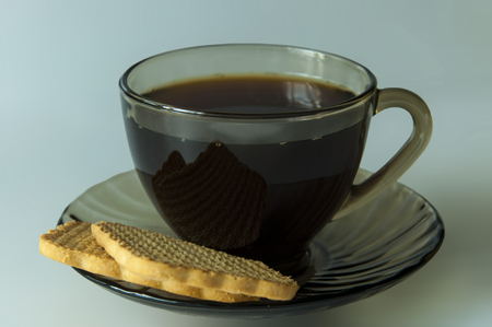 cup of black coffee with biscuits on a glass saucerの写真素材