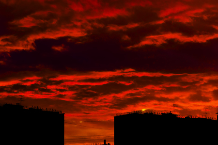 silhouettes of roofs of houses against the background of brightly red evening skyの写真素材
