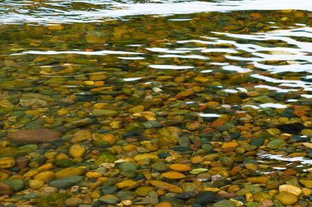 bright colors of small river pebble under waterの写真素材