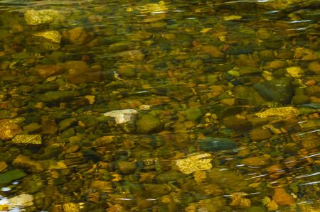 nervousness of water against the background of small river pebble