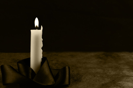 Burning candle with a ribbon on a black-gold backgroundの写真素材