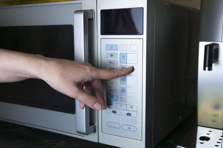Woman's hand. Woman presses the button on the scoreboard microwaveの写真素材