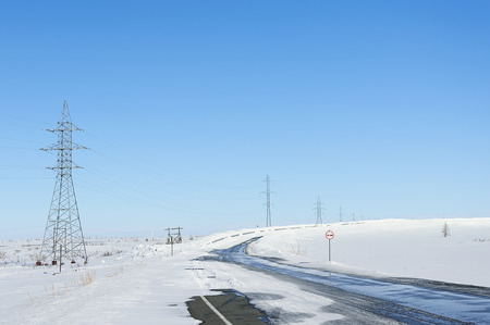 Landscape, road, among the white snow. Supports power lines. Against the blue sky.の写真素材