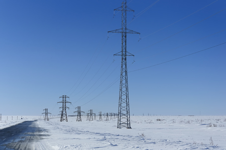 Landscape, road, among the white snow. Supports power lines. Against the blue sky.の写真素材