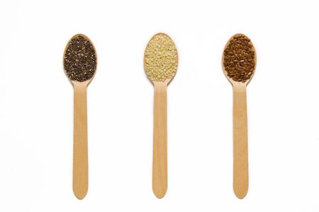 assorted seeds in wooden spoons isolated on white background, chia, linen sesame, healthy food...