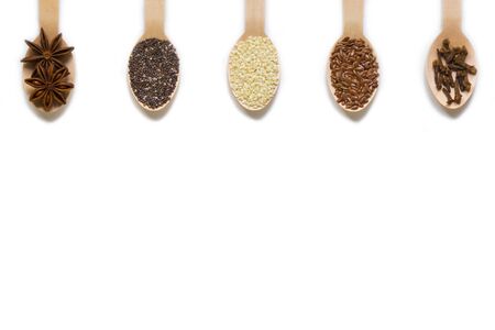 assorted seeds in wooden spoons isolated on white background, chia, linen, sesame, cloves, star anise, healthy food supplements, super food, top view, flat layの写真素材