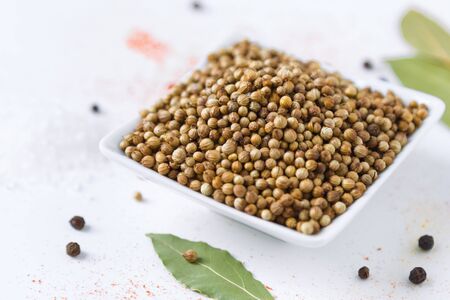 coriander in white bowl and colorful spices on a white backgroundの写真素材