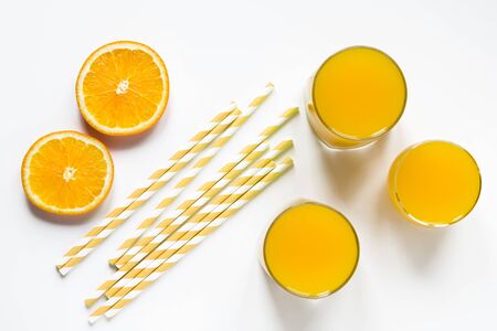 orange smoothies in glasses and paper tubes flat lay top view white backgroundの写真素材