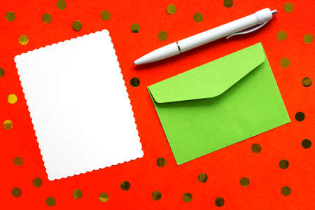 White blank sheet of note in envelope on red background with scattered confetti. Holiday concept.