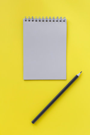 Notebook and pen on yellow background. Color of the Year 2021, stationery concept. Top view, flat...