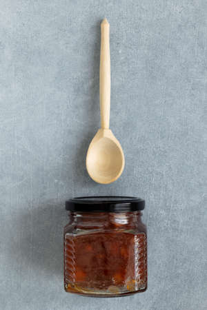 Homemade apple jam in jar with wooden spoon on gray background.の写真素材