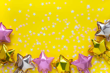Festive concept party background. Greeting card copy space with star balloon and confetti on yellow.の写真素材