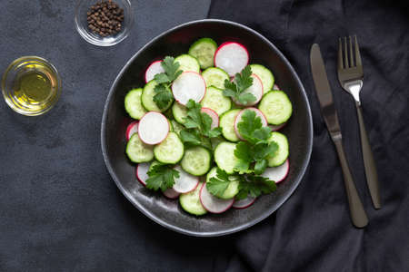 Cucumber and radish fresh salad on black background. Summer menu and vegan.の写真素材