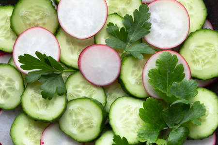 Cucumber and radish fresh salad on black background. Close up.の写真素材