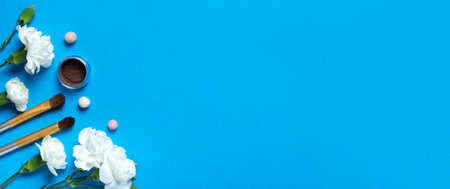 Decorative cosmetics and carnation flower on blue background top view copy space. Concept spring make up. Banner.の写真素材