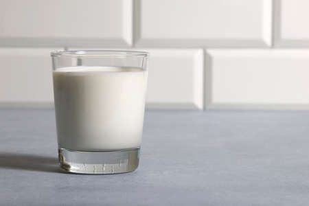 Milk in glass in kitchen on background of tiles on countertop. Closeup copy space.の写真素材