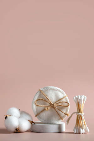 Eco friendly concept. Reusable cotton pads and wooden cotton ear sticks on pastel pink background. Vertical layout.の写真素材