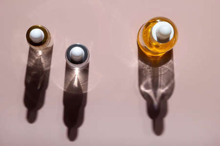 Dropper bottles oil serum gel collagen with hard shadows on pastel neutral pink backgroundの写真素材