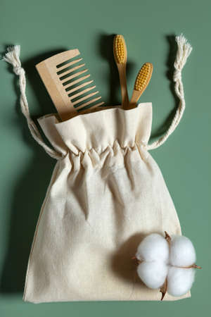 Natural bathroom accessories wooden toothbrushes, hair comb, reusable cotton bag on green background.の写真素材