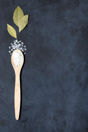 Spices and herbs bay leaf and salt in wooden spoon on black background copy cpace.の写真素材