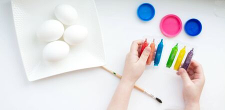 Hands of a little girl draws Easter eggs on a white background.の写真素材