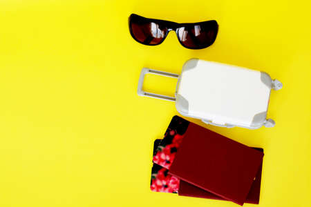 ticket, passport and suitcase, on a yellow background, preparing for the tripの写真素材