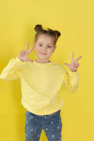 back to school, funny child girl yellow jacket on a yellow background, sitting, reading a book, development and school conceptの写真素材