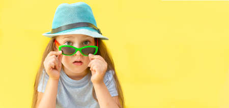 the concept of travel. portrait of a girl in a blue hat with glasses on a yellow background.