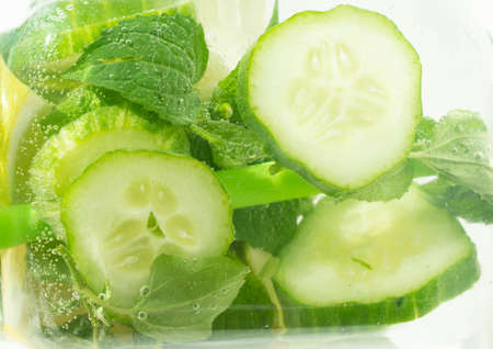 Slice of lemon, lime, cucumber. drop into a sparkling carbonated water, a refreshing juice. background. The concept of healthy eating.の写真素材