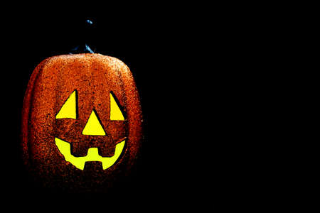 Halloween pumpkin smile and scary eyes for party night. Close up view of scary Halloween pumpkin with eyes glowing inside at black background. Selective focusの写真素材
