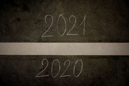 The number of 2020 to 2021 on the asphalt road surface with yellow marking lines, the concept of a happy New year and a productive idea.の写真素材