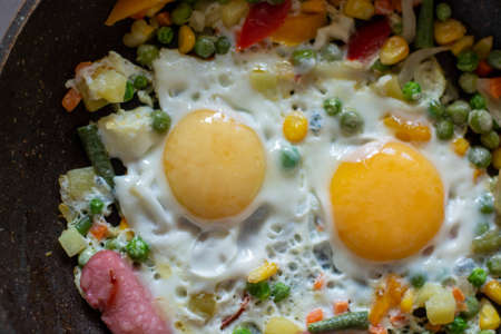 Brunch-fried eggs with vegetables in a frying pan