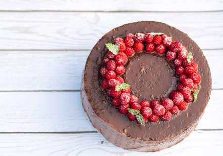 Chocolate cake with raspberries, on a white background of boards.の写真素材