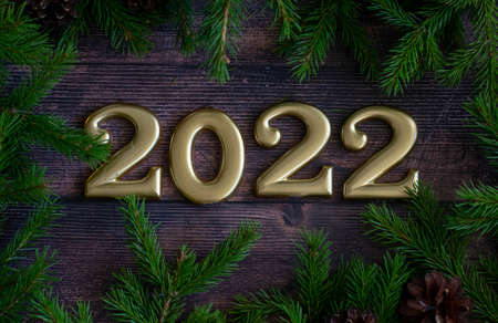 Christmas decoration on a wooden background, fir branches with cones and with the numbers 2022. Top view. Place for textの写真素材