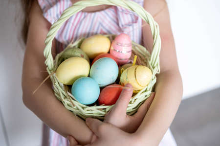 A beautiful child in a bandage with bunny ears, with colorful eggs in a basket, at home in the...