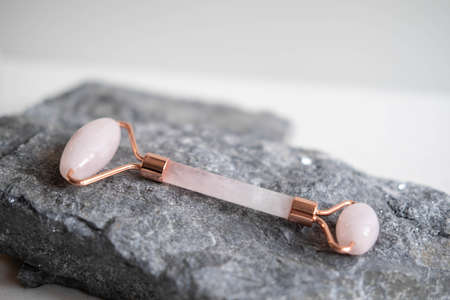 Jade facial roller for cosmetic facial massage lying on a stone. A flat surface on a marble background. Health and beauty.の写真素材