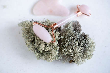Jade facial roller for cosmetic facial massage lying on a natural material - moss. A flat surface on...