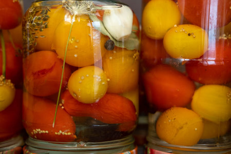 We prepare tomatoes for canning in glass jars. Pickled cherry tomatoes in a jar taken close. Canned tomatoes for the winter.の写真素材