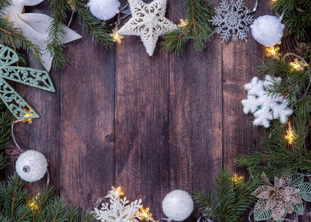 Christmas card. Spruce branches, white balls, snowflakes and a garland are arranged flat on a wooden background. Space for text.の写真素材