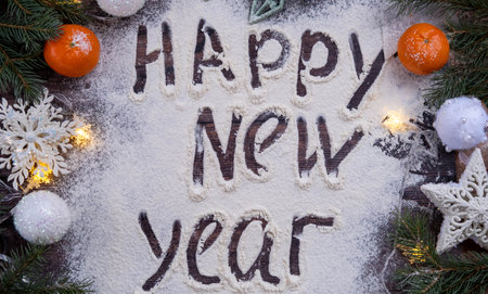 the inscription 2023 is handwritten on flour on a wooden table, next to spruce branches, tangerines and Christmas toys. the concept of the new year.の写真素材