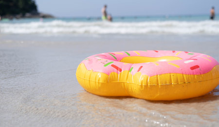 A swimming ring in the form of a donut, on a sandy beach against the background of the sea. Safety for children while bathing. Travel, Tropical summer vacations.の写真素材